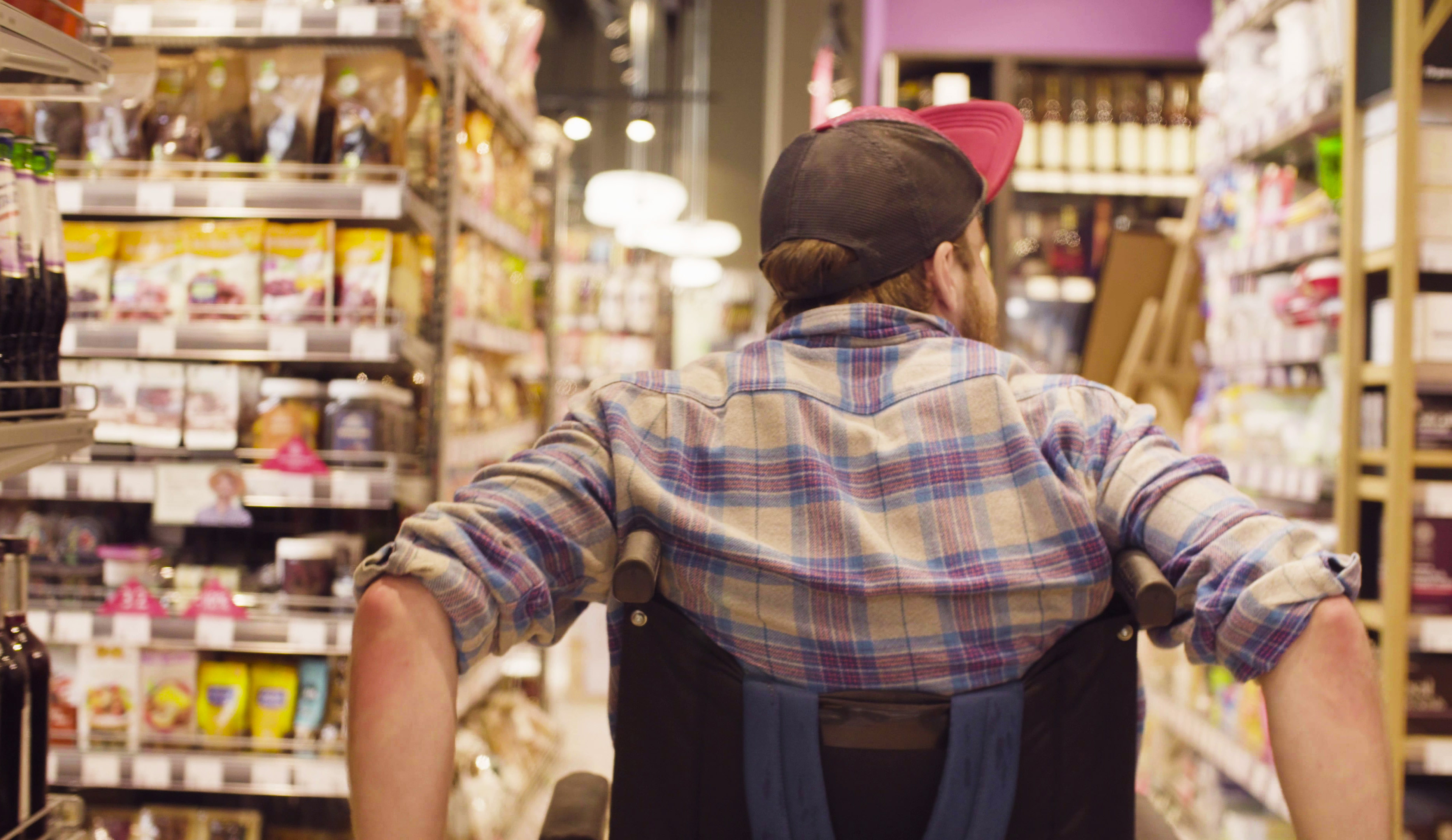 Une personne en fauteuil roulant se déplace dans les allées d'un supermarché